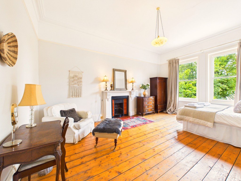 Bright living room with fireplace, wooden floors, white sofa and large windows
