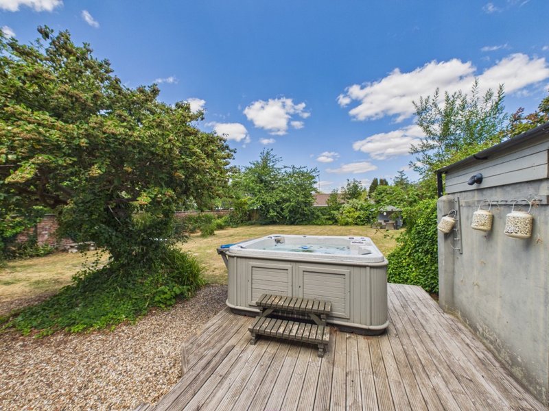 Outdoor hot tub on wooden deck with garden, trees and countryside views