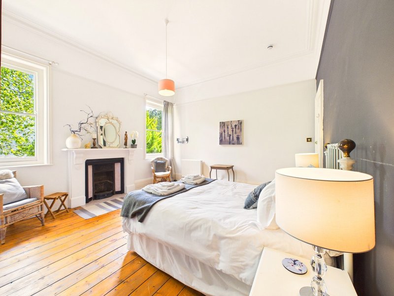 Bright bedroom with double bed, wooden floor, fireplace and pendant light fixture