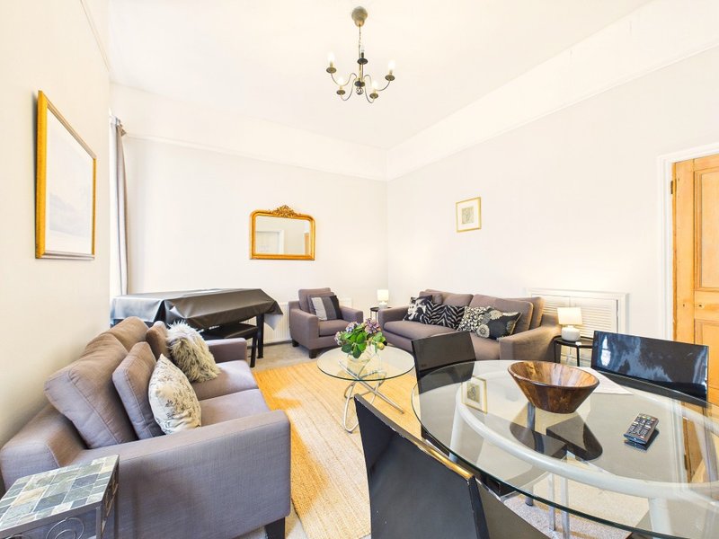 Bright living room with gray sofa, glass coffee table, wooden floor and wall-mounted TV