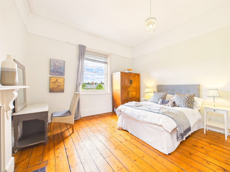 Bright bedroom with wooden floor, double bed, window view, and bedside lamps