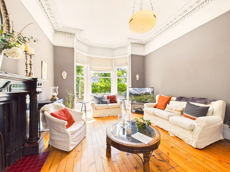 Bright living room with cream sofas, wooden floors, large windows and decorative cushions