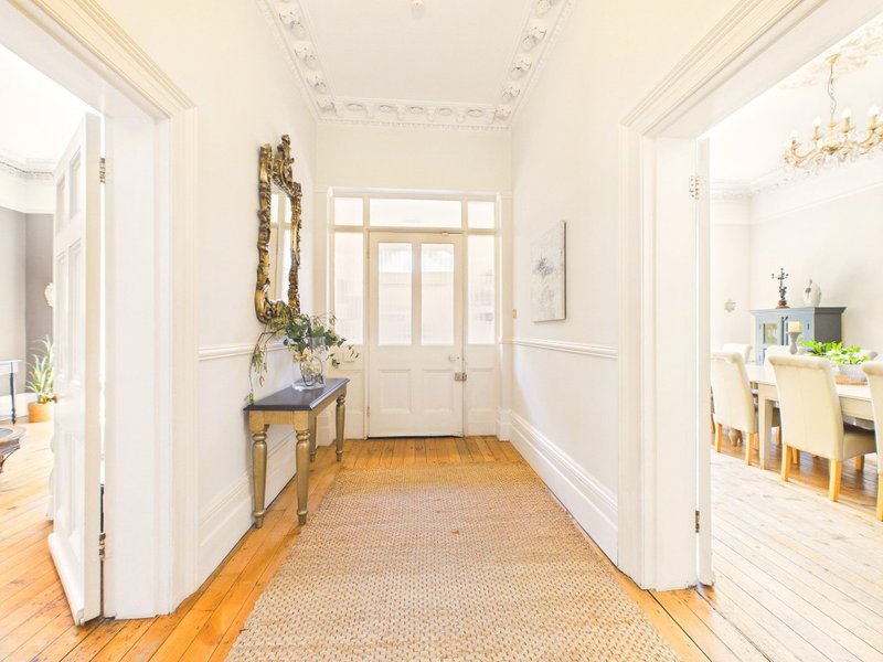 Bright hallway with wooden floor, white walls, console table with mirror and decorative wreath
