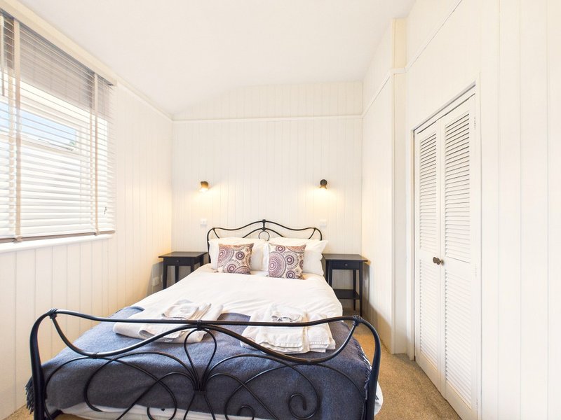 Bright bedroom with ornate black metal bed frame, white bedding, twin bedside tables, and wall sconces