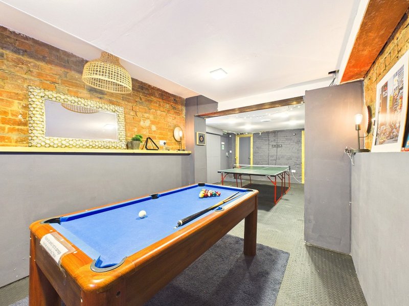 Recreation room with blue pool table, exposed brick wall, and bathroom entrance