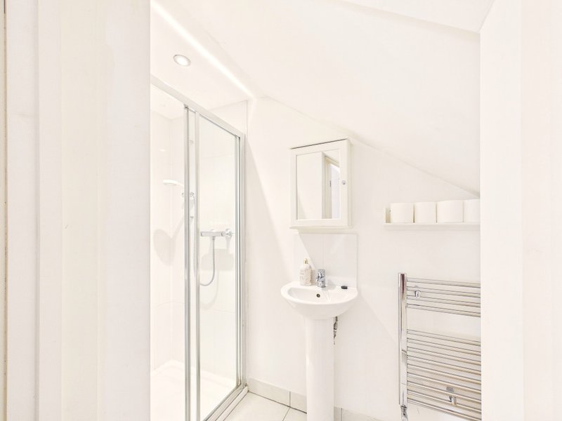 Clean modern bathroom with shower enclosure, pedestal sink, and heated towel rail
