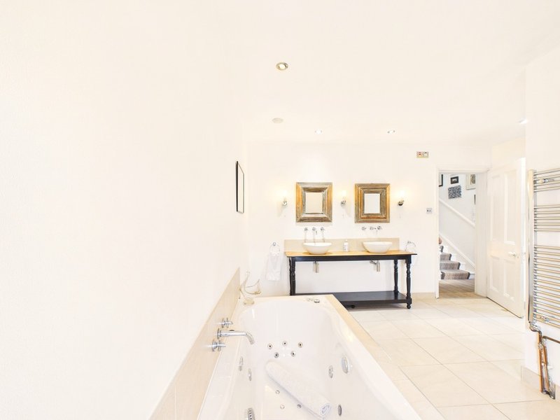 Spacious bathroom with freestanding bathtub, vanity sink, mirrors and heated towel rail