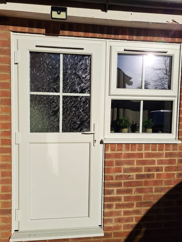 Brick exterior with white entrance door, four-pane window, and side window