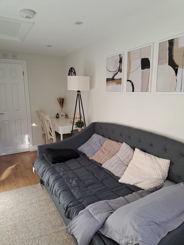Modern bedroom with dark upholstered bed, colorful pillows, tripod lamp and abstract wall art