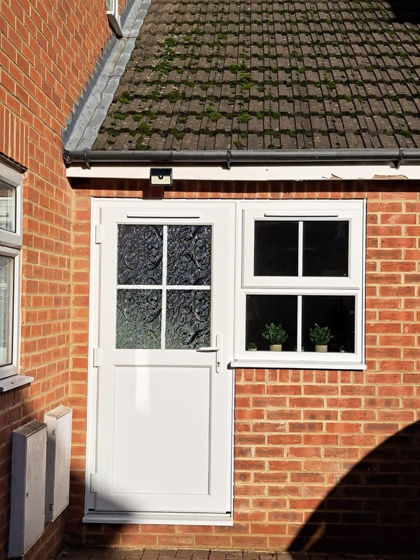 Brick residential building exterior with white door, windows and tiled roof