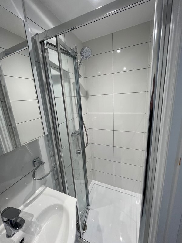 Modern bathroom with walk-in shower enclosure, white tile walls and chrome fixtures