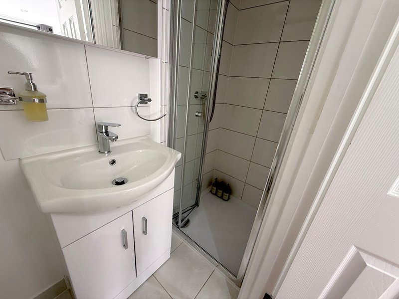 Clean bathroom with white sink vanity, mirror, and enclosed shower cubicle