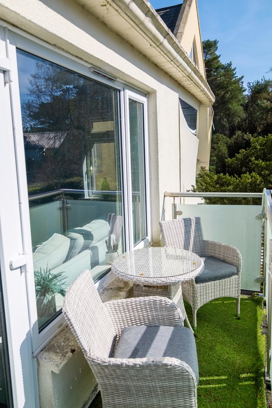 Outdoor patio with wicker furniture, round table, and view into bedroom through glass doors