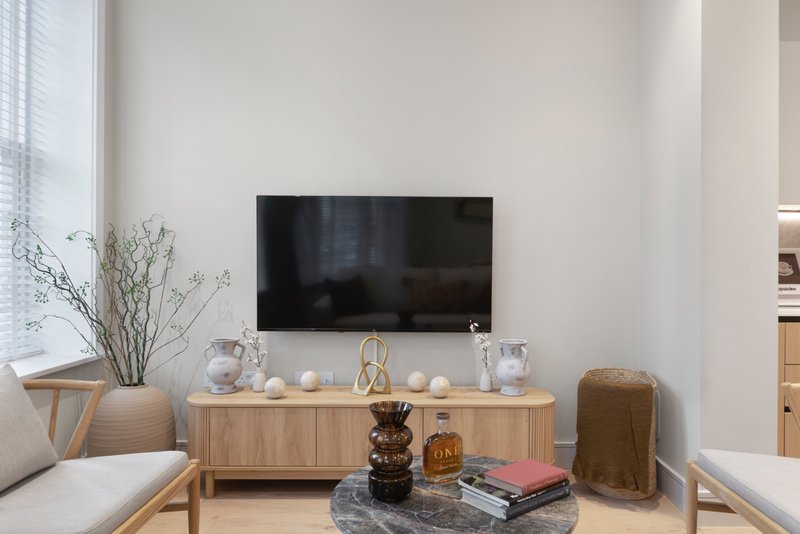Modern living room with wall-mounted TV, wooden media console, and minimalist decor