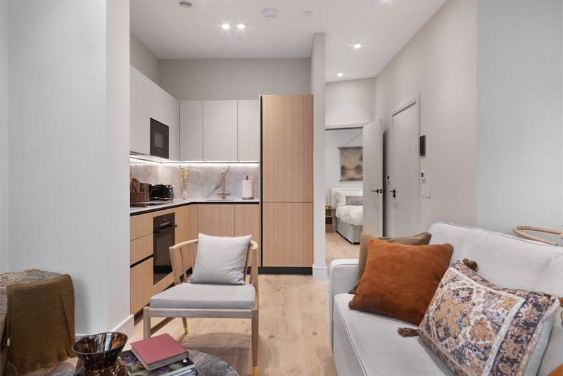 Studio apartment with open-plan kitchen, bed, chair, and modern furnishings throughout