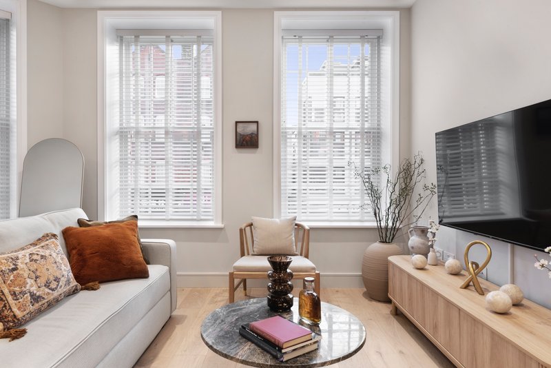 Bright living room with white sofa, wooden TV unit, round coffee table and large windows