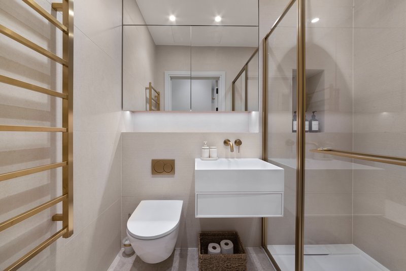 Modern bathroom with white toilet, floating vanity, mirror, and walk-in shower enclosure
