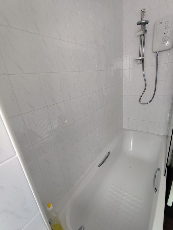 Modern bathroom with white tiled shower enclosure, chrome fixtures and rainfall showerhead