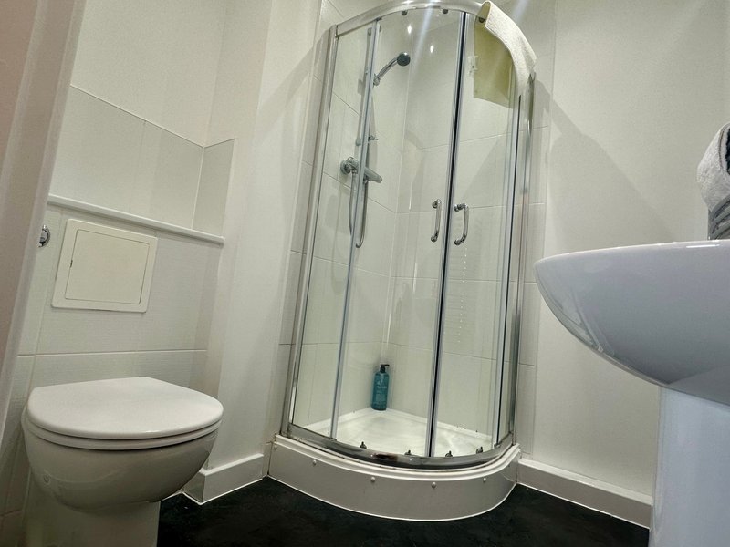 Modern bathroom with white toilet, curved glass shower enclosure and wall-mounted sink