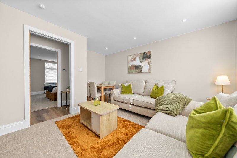 Modern living room with cream sofa, lime green cushions, wooden coffee table and orange rug