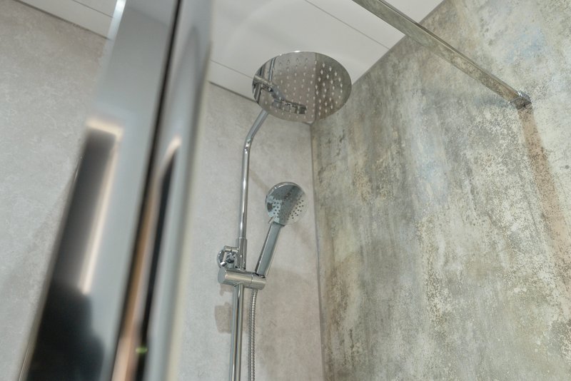 Bathroom shower head and handheld spray mounted on tiled wall