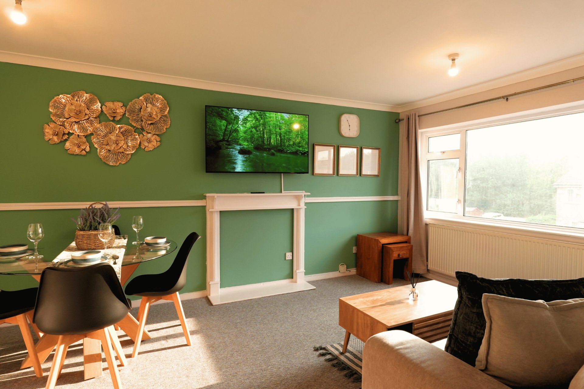 Open-plan living and dining room with green walls, TV, wooden furniture and large windows