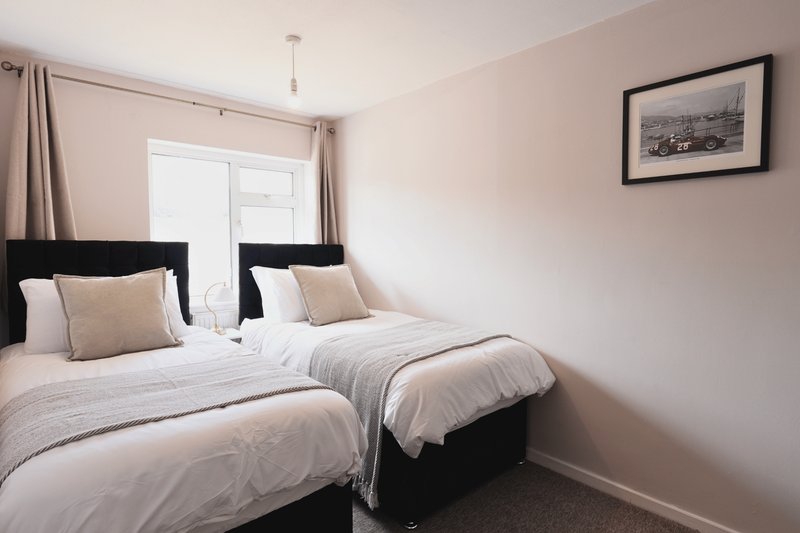 Twin bedroom with two single beds, black headboards, neutral bedding and framed artwork