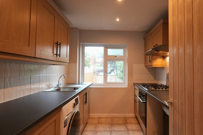 Modern kitchen with wooden cabinets, black countertop, stove and window