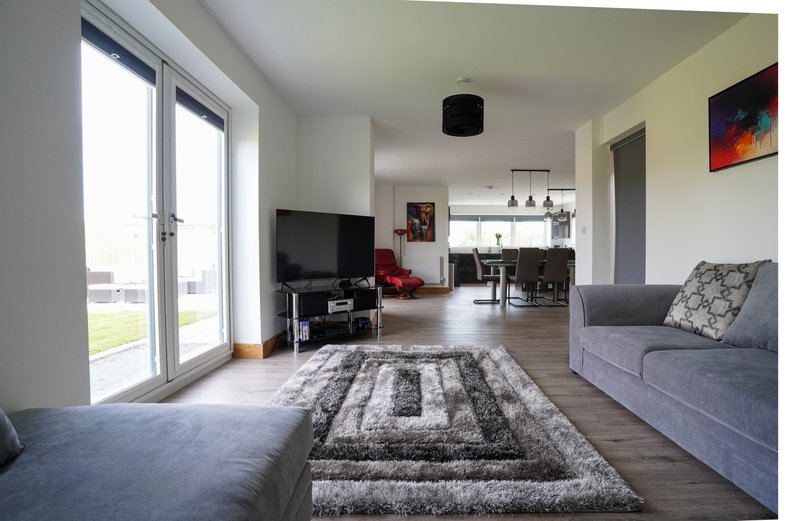 Comfortable sofas, a large TV and generous floor space create a welcoming place to unwind, while the open layout leads through to the dining area and fully equipped kitchen.