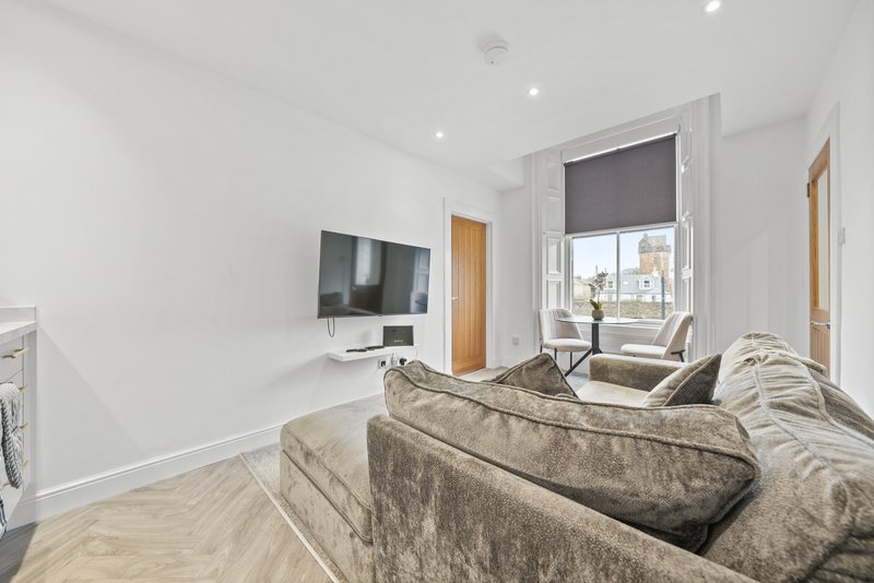 Modern living room with beige sofa, wall-mounted TV, wooden flooring and large window