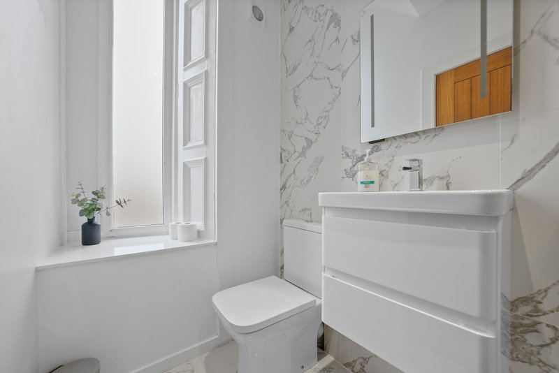 Modern bathroom with white vanity, toilet, marble backsplash and window