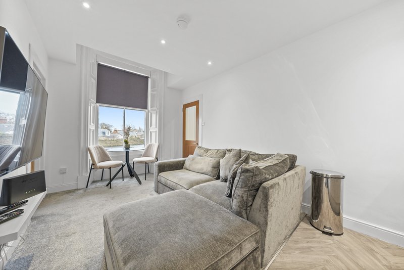 Bright living room with beige sofa, armchair, wooden floor and city views