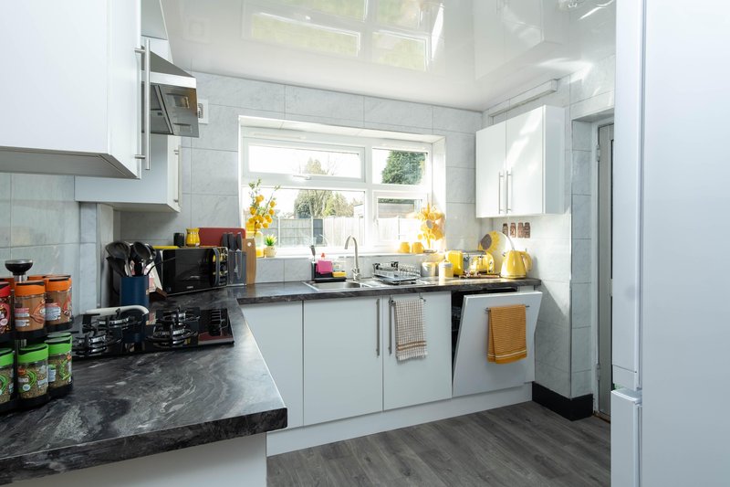 Modern kitchen with white cabinets, black countertop, stainless steel appliances and window