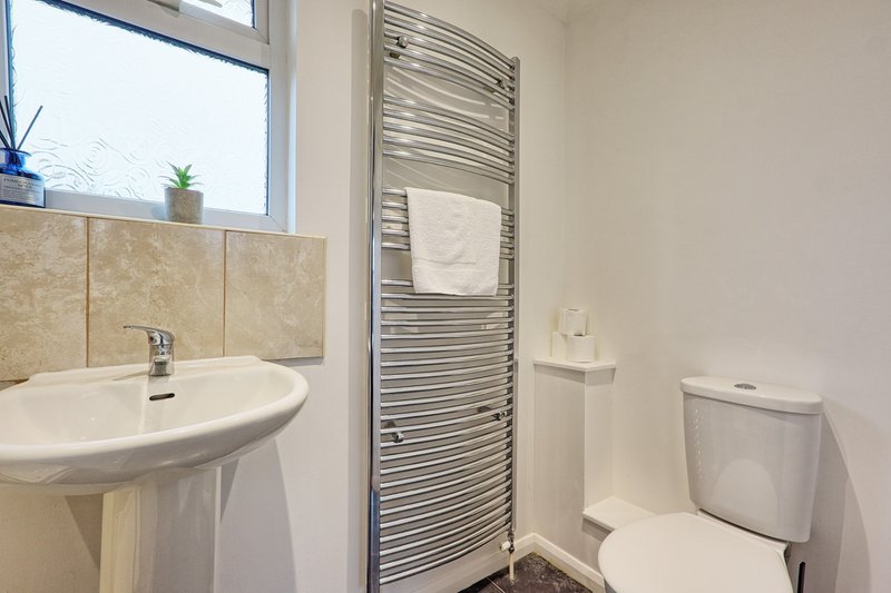 Bright bathroom with round sink, heated towel rail, toilet and window