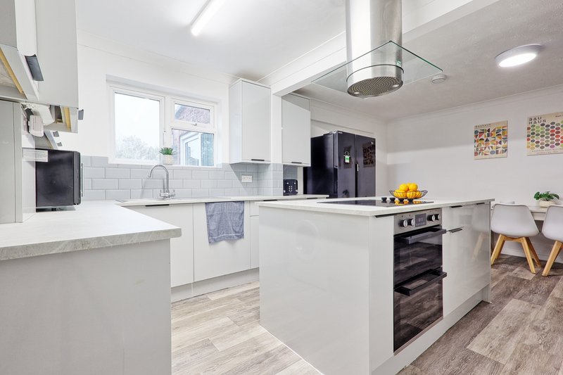 Modern white kitchen with island, stainless steel appliances, and dining area