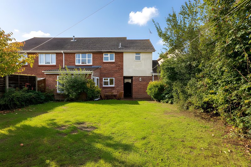 Brick detached house with garden, lawn, and mature hedging surrounding property