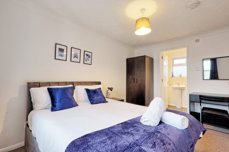 Bedroom with double bed, blue pillows and bedding, wooden headboard, pendant light