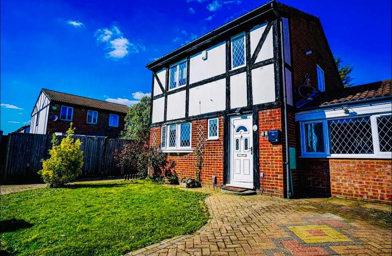 Tudor-style brick house with black and white timber framing, front garden and driveway