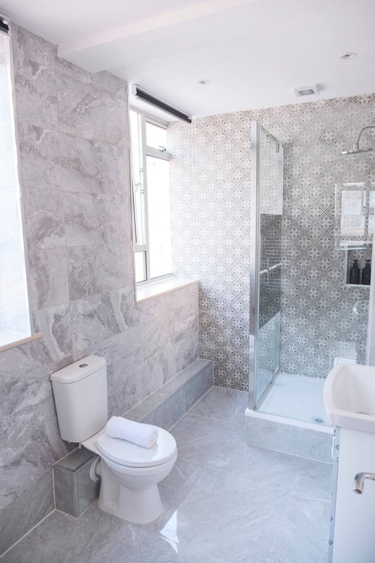 Modern bathroom with toilet, bathtub, walk-in shower and tiled walls