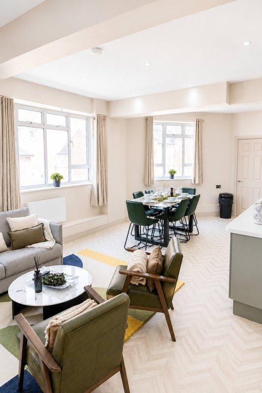Open-plan living and dining area with sofa, armchairs, dining table and large windows