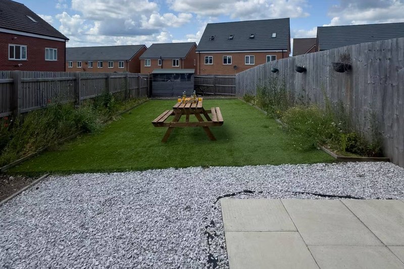 Rear garden with picnic table, lawn, gravel patio and wooden fencing
