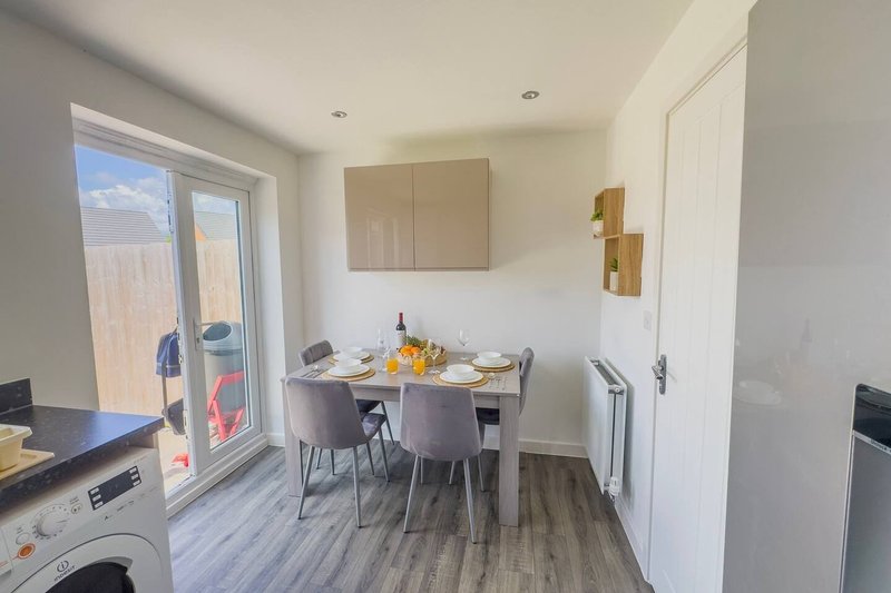 Open-plan kitchen and dining area with table, chairs, appliances and patio doors