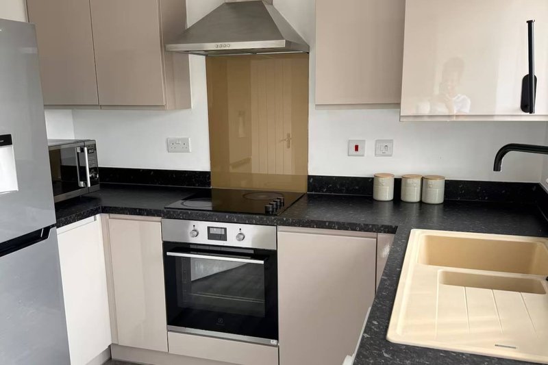 Modern kitchen with white cabinets, black countertop, built-in oven and hob