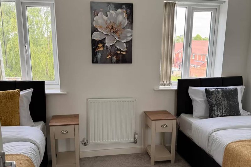 Twin bedroom with two beds, wooden nightstands, radiator and window views