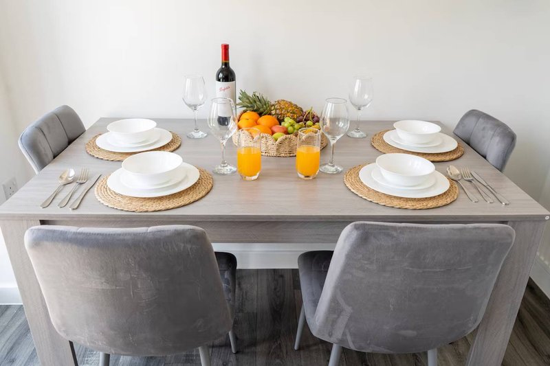 Dining table set for four with wine bottle, glasses, place settings and fruit centerpiece