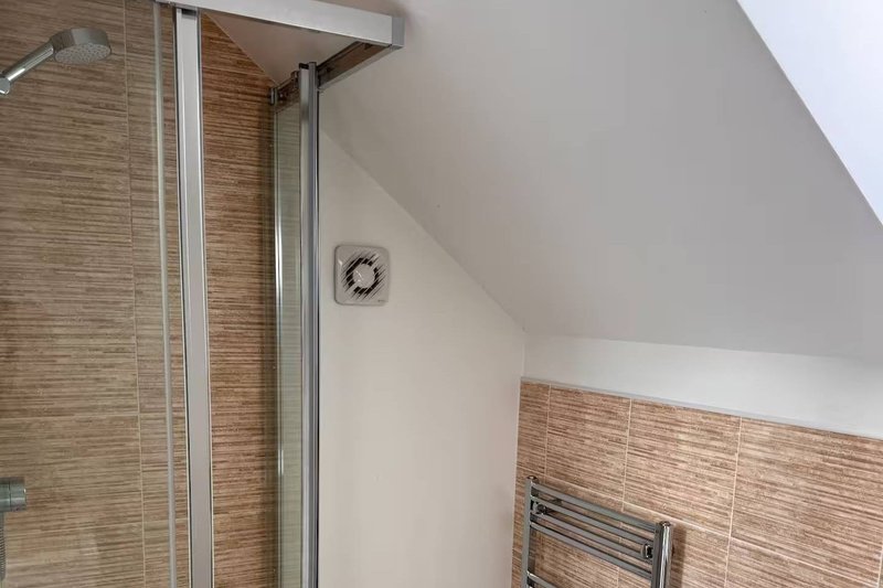 Bathroom with walk-in shower, glass enclosure, wooden tile walls and heated towel rail