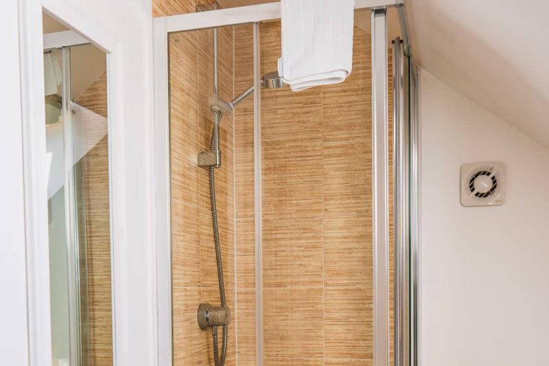 Modern bathroom shower enclosure with wooden tile walls and chrome fixtures