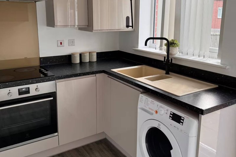 Modern kitchen with white cabinets, black countertops, integrated appliances and window