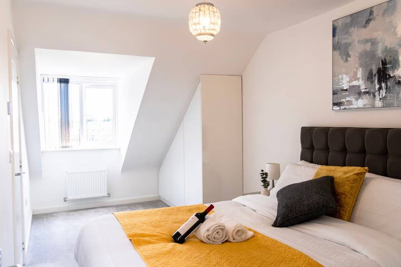Bright bedroom with double bed, black headboard, yellow bedding, skylight window and pendant lamp