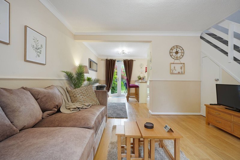 Open-plan living room with beige sofa, wooden coffee table, wall art and clock